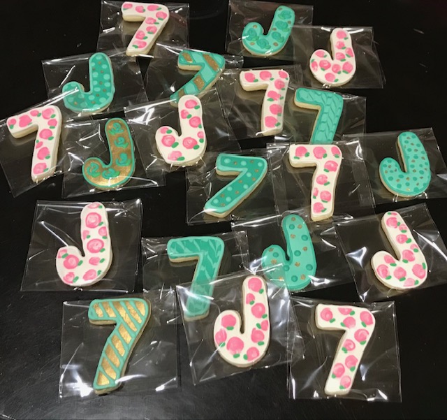 Cookies decorated in green frosting shaped like the number seven.
